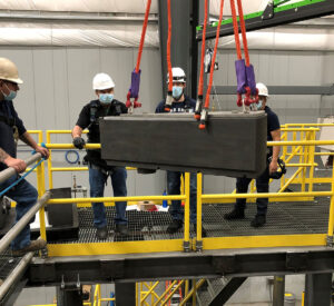 Workers lower a graphite reflector block into the ETU vessel