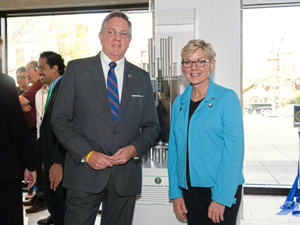 Secretary of Energy Jennifer Granholm and Kairos Power VP of Regulatory Affairs and Quality Peter Hastings stand in front of a scale model of the Hermes demonstration reactor at DOE headquarters